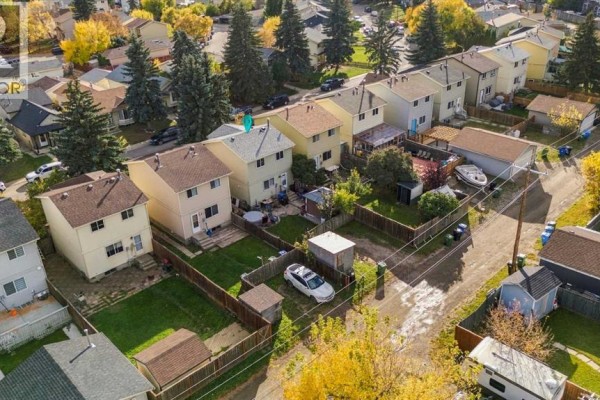 Aerial view of the backyards of houses on a residential street with fences and sheds. - 17 Erin Ridge Road Se, Calgary