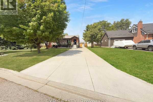 Long concrete driveway leading to the house, flanked by green grass and trees. - 17 Greenfield Court, London South