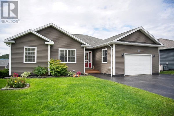 Front exterior of a single-story house with brown siding, white trim, and attached garage. - 17 Hann Crescent, Corner Brook