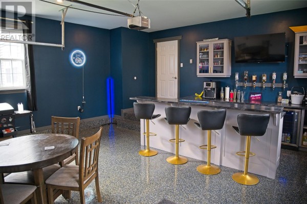 Home bar area with dark blue walls, grey countertop, and four gold-legged bar stools. - 17 Hann Crescent, Corner Brook