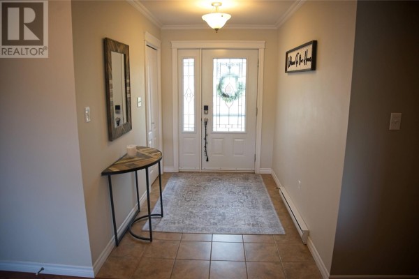 Entrance to a residential house with a red front door, screen door, and adjacent garage. - 17 Hann Crescent, Corner Brook