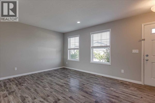Interior entryway with beige walls, white door, closet, and wood-look laminate flooring. - 17 Hawthorn Place, Sylvan Lake