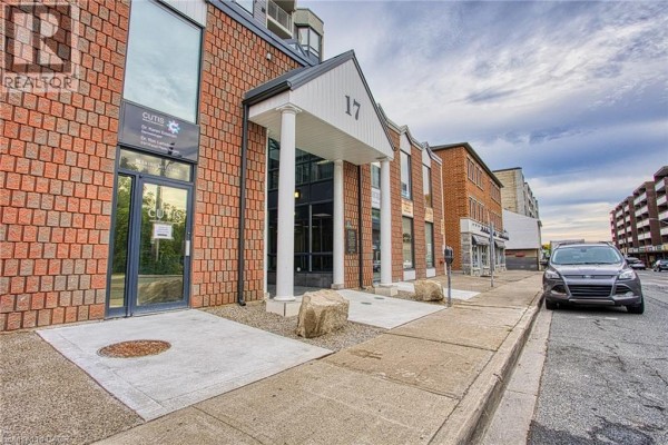 Exterior view of brick building entrance with columns and signage. - 17 King Street E Unit# 502, Dundas