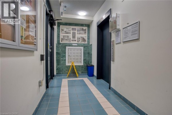 Building hallway with blue tiled floor, mailboxes, and elevator. - 17 King Street E Unit# 502, Dundas