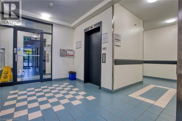 Building hallway with blue and white checkered floor and elevator. - 17 King Street E Unit# 502, Dundas