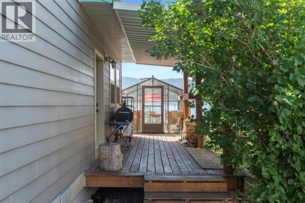 Wooden deck on the side of a house with a barbecue and a greenhouse beyond. - 17 Mary's Emerald Bay Road, Vernon