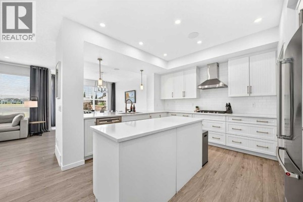 Modern white kitchen with a large island, stainless steel appliances, and white subway tile backsplash. - 17 Masters Terrace Se, Calgary