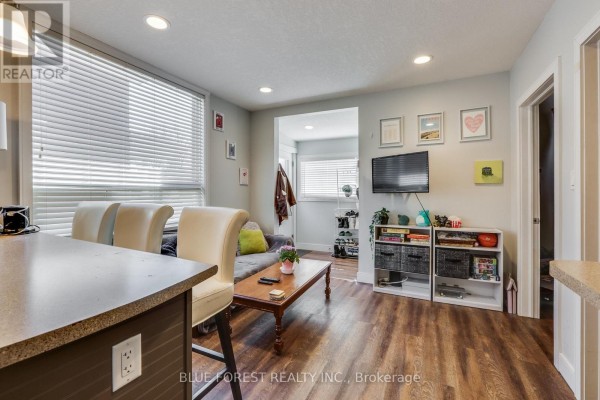Bedroom with a white bed, green accent wall, white blinds, and wood-look laminate flooring. - 17 Mcdonald Avenue, London North
