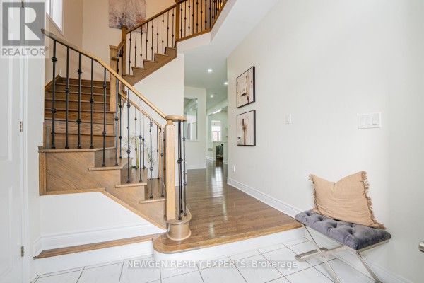 Interior foyer with wooden staircase, hardwood flooring, and decorative wall art. - 17 Monarch Drive, Halton Hills
