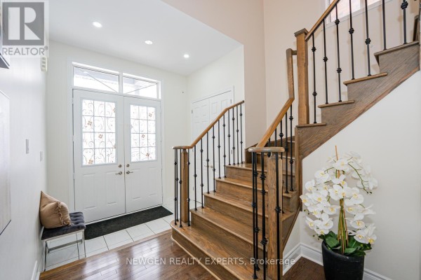 Bright entryway featuring a staircase, large windows, and potted plants. - 17 Monarch Drive, Halton Hills