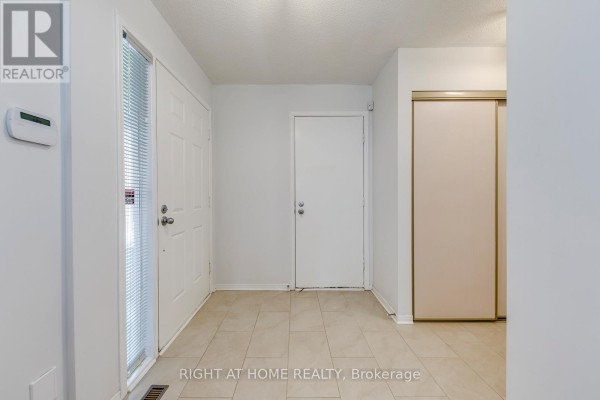 Interior foyer with beige tile floor, white double doors, and a closet. - 17 Nickel Crescent, Brampton