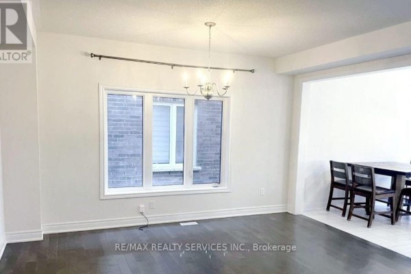 Dining area with large window, chandelier, and adjacent open space, hardwood flooring. - 17 Overstone Road E, Halton Hills