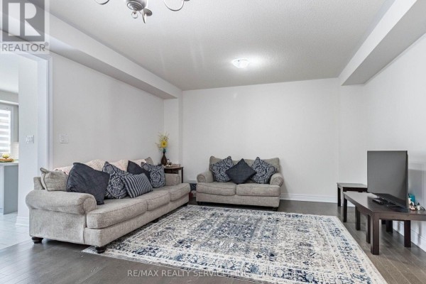 Living room with two sofas, decorative pillows, and a patterned area rug, neutral wall color. - 17 Overstone Road E, Halton Hills