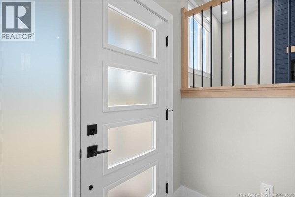 Interior view of the modern white front door with black hardware and frosted glass. - 17 Robert Street, Shediac