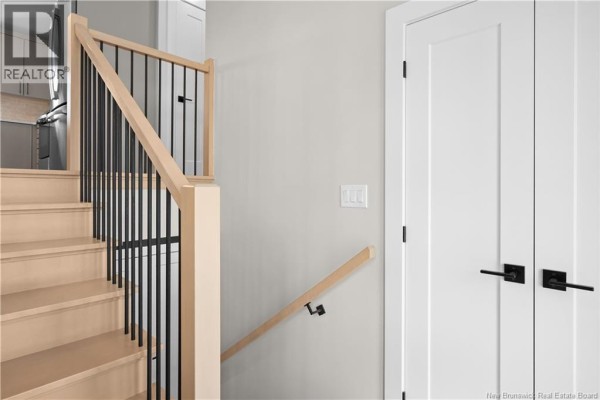 Wooden staircase with black metal spindles and a light grey wall. - 17 Robert Street, Shediac