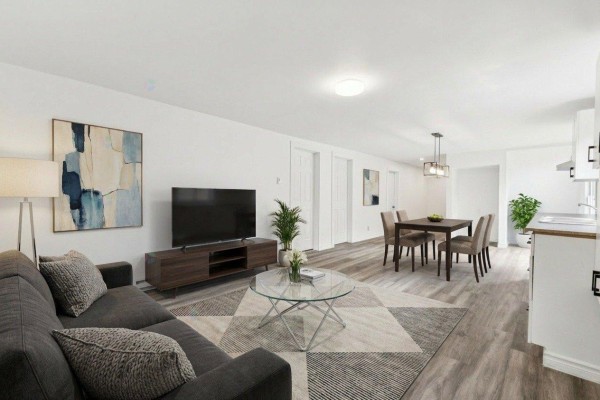 Spacious living area with gray laminate flooring and white walls - 17 Rue Blais, Val Des Monts
