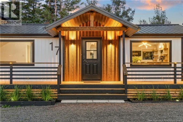 Front view of the house entrance with a black door, wood accents, and large windows on either side. - 17 Sandpiper, Grande Digue