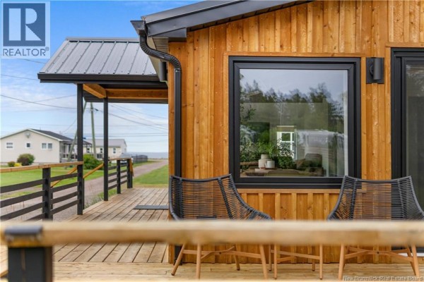 Deck seating area with two wicker chairs facing a large window with reflection of the interior. - 17 Sandpiper, Grande Digue