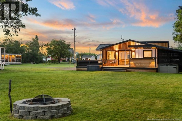 Backyard view of the house at sunset, with a fire pit in the foreground and lawn. - 17 Sandpiper, Grande Digue
