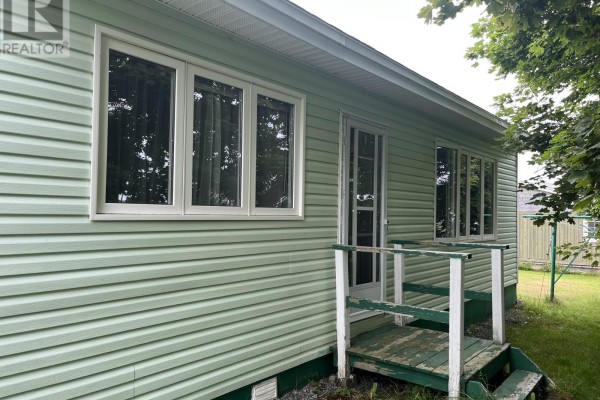 Exterior of a light green vinyl-sided house showing a door and windows with white trim. - 17 View Lane, Conception Bay South