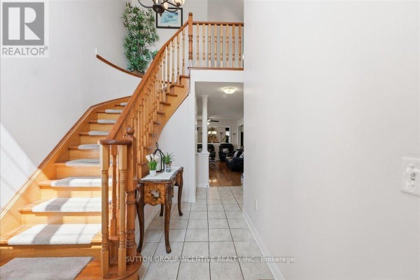 Curved wooden staircase and tile hallway with console table - 17 White Crescent Barrie