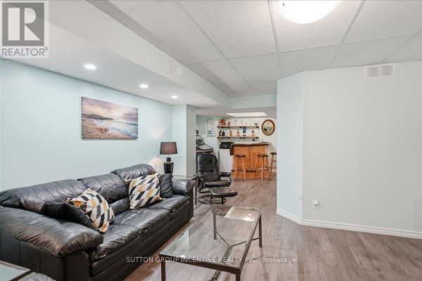 Basement living room with black leather sofa, bar, and artwork - 17 White Crescent Barrie