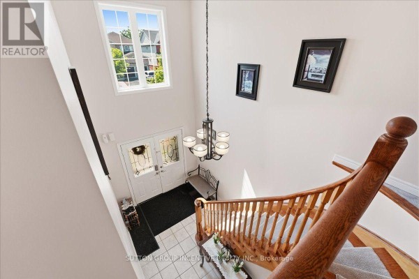 Interior view of the foyer with a grand staircase, double doors, and large window overlooking the street. - 17 White Crescent, Barrie