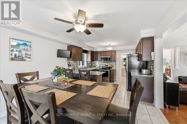 Kitchen with dark wood cabinets, island, and dining area - 17 White Crescent Barrie