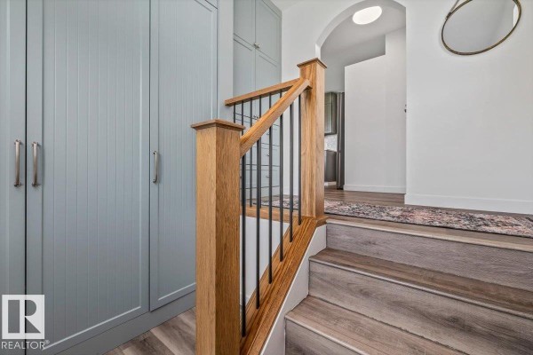 Interior view of a staircase with oak banister and black spindles, next to pale blue cabinets. - #170 22169 Twp Road 530, Rural Strathcona County