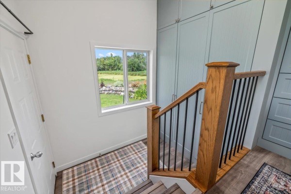 View from top of stairs looking down, with a window showing a green rural landscape. - #170 22169 Twp Road 530, Rural Strathcona County
