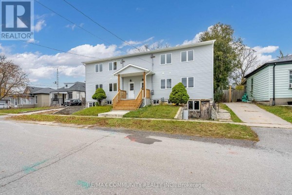 Street view of a two-story grey duplex building with lawns and surrounding houses. - 170 Bruton Street, Port Hope