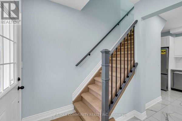 Interior staircase with light blue walls, beige carpeted steps, and black railing. - 170 Bruton Street, Port Hope