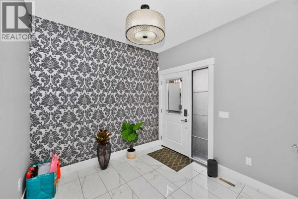 Foyer with black and white damask wallpaper, white tile floors, and a white door. - 170 Kinniburgh Crescent, Chestermere