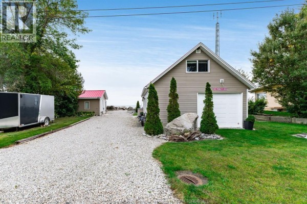 Gravel driveway leading to a detached garage with two garage doors and exterior siding. - 170 Lakeshore Road, Leamington