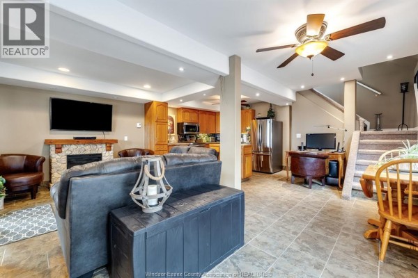 Living room with a leather sofa, fireplace, wood cabinets, stainless steel appliances, and stairs. - 170 Lakeshore Road, Leamington
