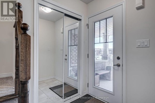 Interior entryway with mirrored closet doors, tiled floor, and carpeted stairs leading up. - 170 Maclachlan Avenue, Haldimand