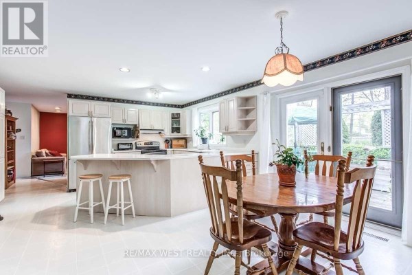 Kitchen and dining area with white cabinets, stainless steel appliances, and a round wooden table. - 170 Newton Drive, Toronto