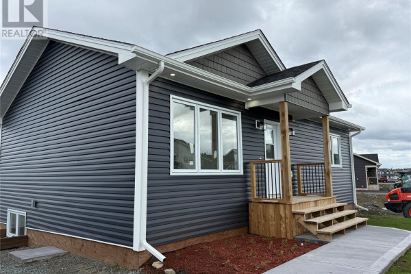 Side exterior of a dark gray vinyl-sided bungalow showing the entrance porch with wooden stairs. - 170 Penwell Avenue, Gander