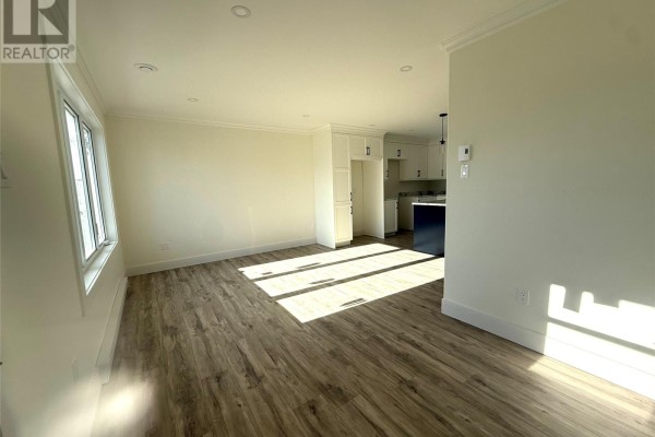 Living room with light wood laminate flooring and a large window with sun glare. - 170 Penwell Avenue, Gander