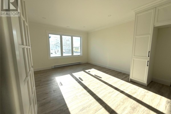 Room with light wood laminate flooring, a large window, and a tall white cabinet. - 170 Penwell Avenue, Gander