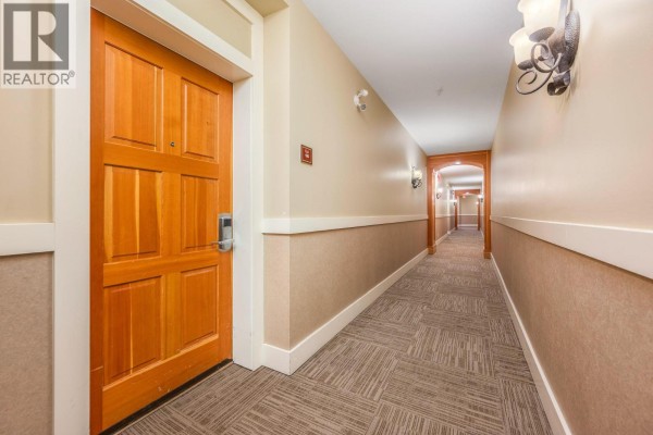 Hallway with a wooden door on the left, patterned carpet, and decorative wall sconces. - 170 Silver Lode Lane Lane Unit# 105, Silver Star