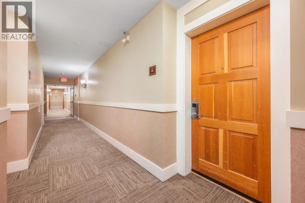 Long hotel-style hallway with beige walls, carpeted floor, and wooden doors. - 170 Silver Lode Lane Lane Unit# 304, Silver Star