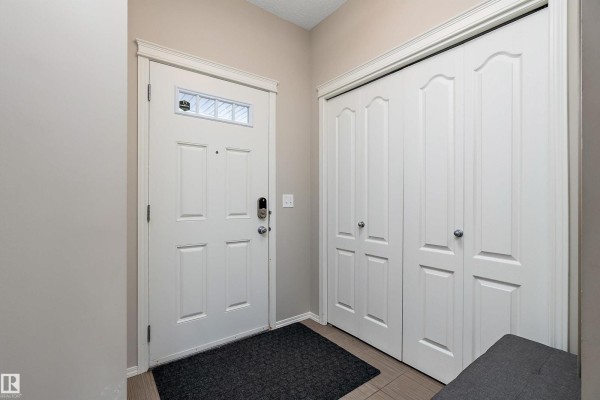Interior entryway with a white door, a large closet with bi-fold doors, and a tiled floor. - 17005 120 St Nw, Edmonton