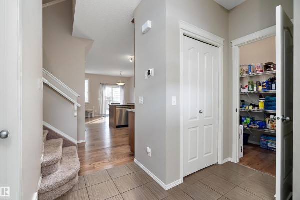 Interior hallway looking towards the kitchen and dining area, with a staircase and pantry. - 17005 120 St Nw, Edmonton