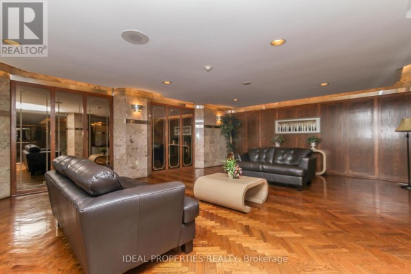 Lobby seating area with brown leather sofas, wood parquet floor, and wood-paneled walls. - 1701 - 2759 Carousel Crescent, Ottawa