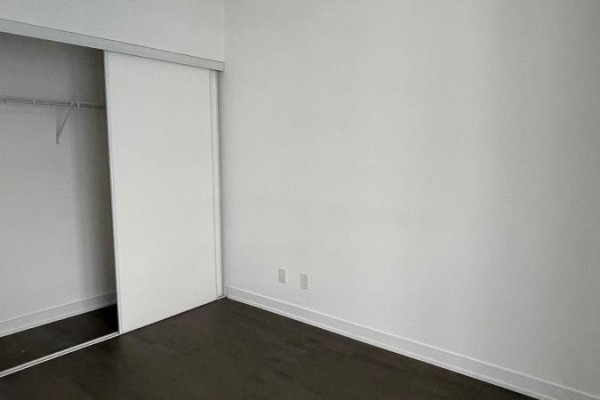 View of an empty bedroom with white walls and a closed sliding closet door. - 1701 - 57 St Joseph Street, Toronto