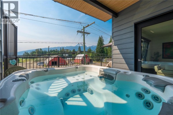 Cozy bedroom with a queen bed, artwork, and a window overlooking the exterior. - 1701 Coursier Avenue Unit# 2213, Revelstoke