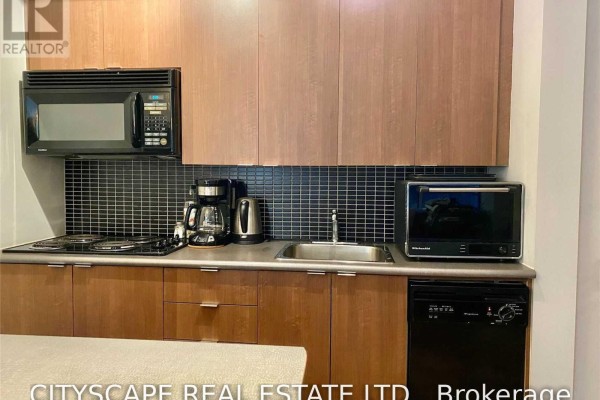 Kitchen counter with a coffee maker, sink, stove, microwave, and compact refrigerator. - 1702 - 8 Colborne Street, Toronto