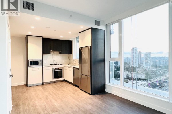 Apartment living area and kitchen with large windows and city views. - 1702 567 Clarke Road, Coquitlam