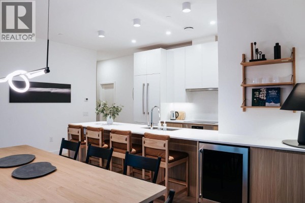 Dining area with wooden table, black chairs, and adjacent kitchen space - 1702 Coursier Avenue Unit# 2501, Revelstoke